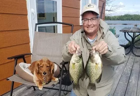 Women Holding Up Two Crappie Fish Beside Dog Aspect Ratio 320 220